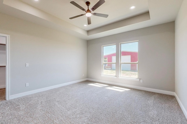 spare room with ceiling fan, a raised ceiling, and carpet