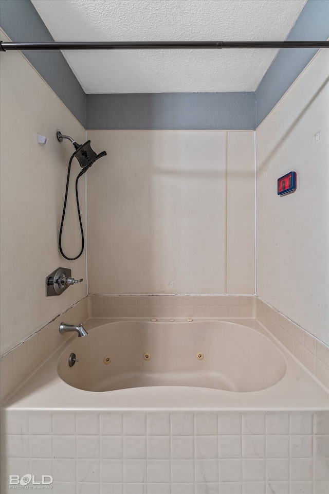 bathroom featuring a textured ceiling and tiled tub