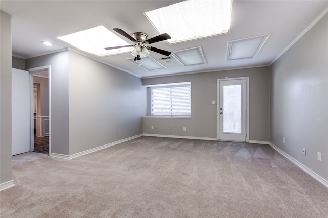 carpeted empty room featuring ornamental molding, ceiling fan, and a skylight