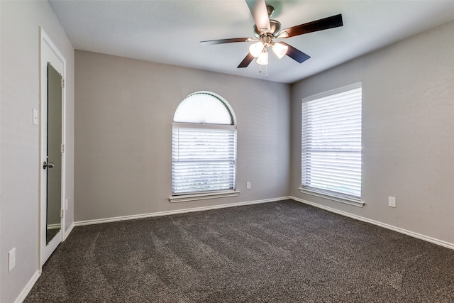 carpeted empty room with ceiling fan and a wealth of natural light