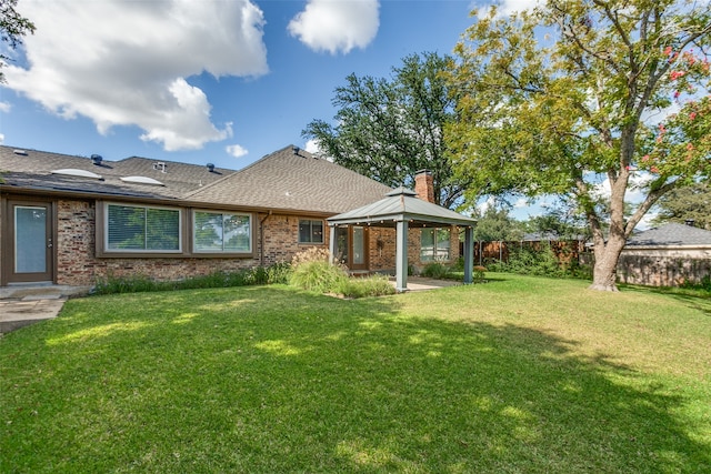 back of property featuring a gazebo and a yard