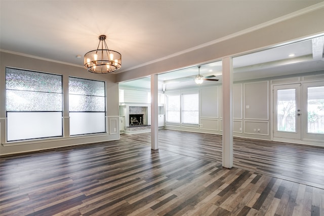 unfurnished living room with a healthy amount of sunlight, ceiling fan with notable chandelier, crown molding, and dark hardwood / wood-style floors