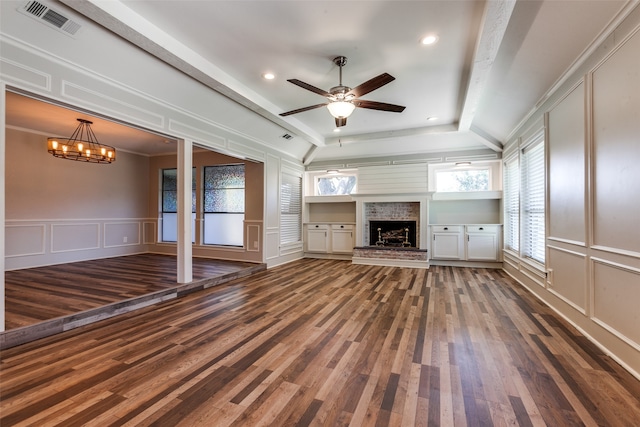 unfurnished living room with ceiling fan with notable chandelier, a fireplace, and dark hardwood / wood-style floors