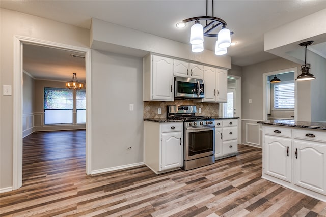 kitchen with pendant lighting, a chandelier, white cabinetry, light hardwood / wood-style flooring, and stainless steel appliances