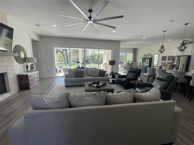 living room featuring ceiling fan, a fireplace, and wood-type flooring