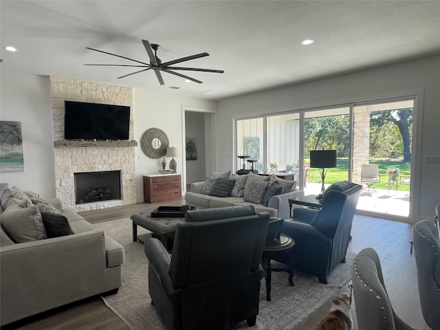 living room with a fireplace, hardwood / wood-style floors, a textured ceiling, and ceiling fan