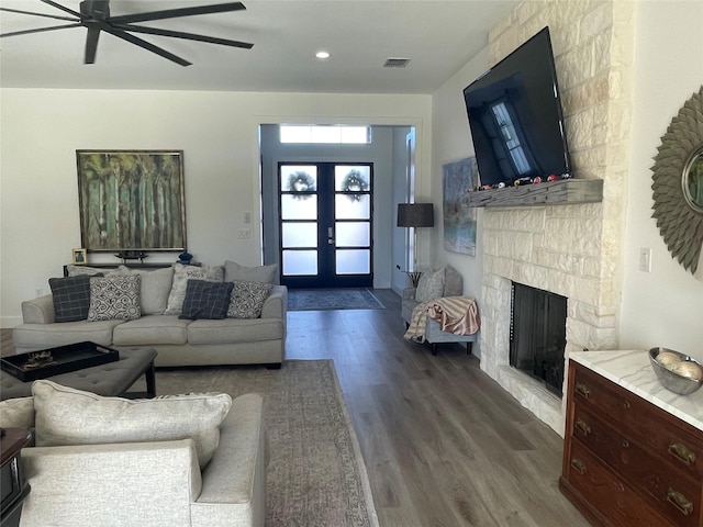 living room featuring hardwood / wood-style floors, a stone fireplace, french doors, and ceiling fan