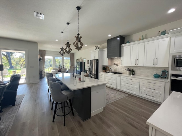 kitchen featuring white cabinetry, an island with sink, appliances with stainless steel finishes, and dark wood-type flooring