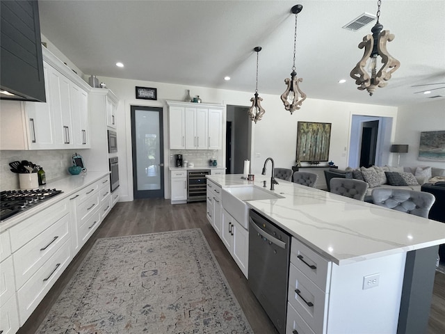 kitchen featuring sink, stainless steel appliances, decorative light fixtures, a center island with sink, and white cabinets