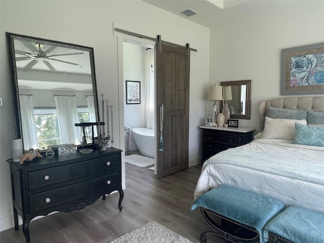 bedroom with a barn door, hardwood / wood-style flooring, and connected bathroom