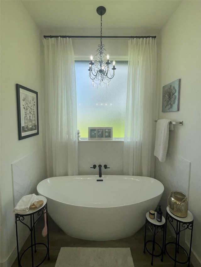 bathroom featuring a washtub and a notable chandelier