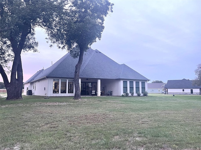 back house at dusk featuring central AC and a yard