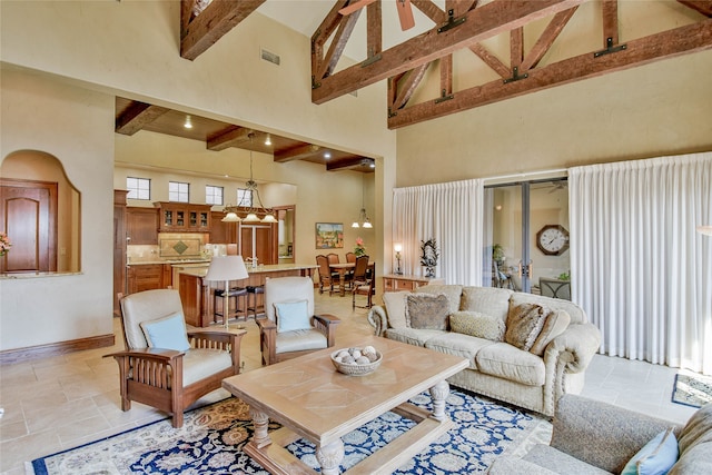 living room with beamed ceiling, high vaulted ceiling, and ceiling fan with notable chandelier