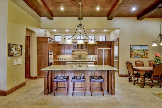 kitchen with a center island with sink, beam ceiling, wood ceiling, and hanging light fixtures