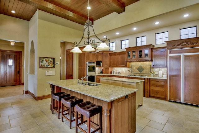 kitchen featuring sink, stainless steel appliances, wooden ceiling, pendant lighting, and a center island with sink