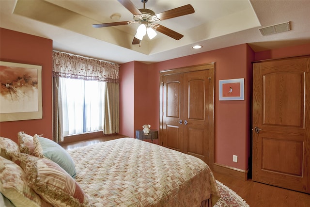 bedroom featuring light hardwood / wood-style flooring, a raised ceiling, and ceiling fan