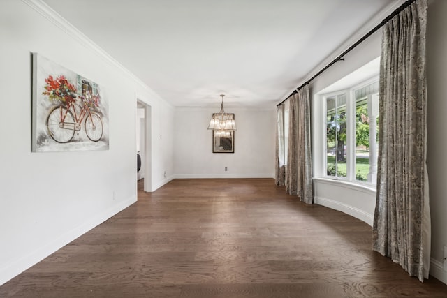 empty room featuring dark hardwood / wood-style flooring, ornamental molding, and an inviting chandelier