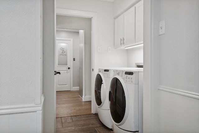 clothes washing area with washer and clothes dryer, cabinets, and dark wood-type flooring