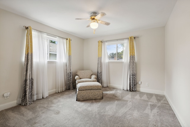 living area with ceiling fan, a healthy amount of sunlight, and light colored carpet