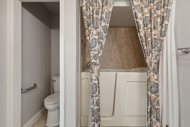 bathroom featuring tile patterned flooring, toilet, and a washtub