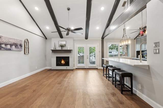 living room featuring a fireplace, lofted ceiling with beams, light hardwood / wood-style flooring, and ceiling fan