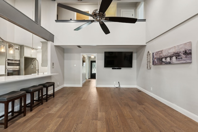 living room featuring ceiling fan, dark hardwood / wood-style flooring, a high ceiling, and sink