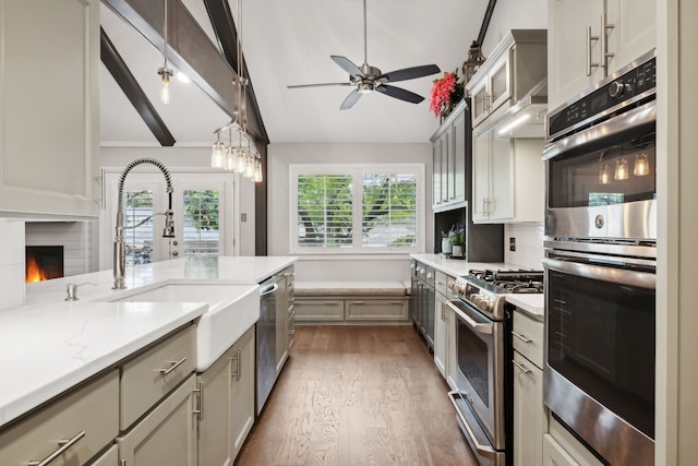 kitchen featuring sink, dark wood-type flooring, stainless steel appliances, vaulted ceiling with beams, and decorative backsplash