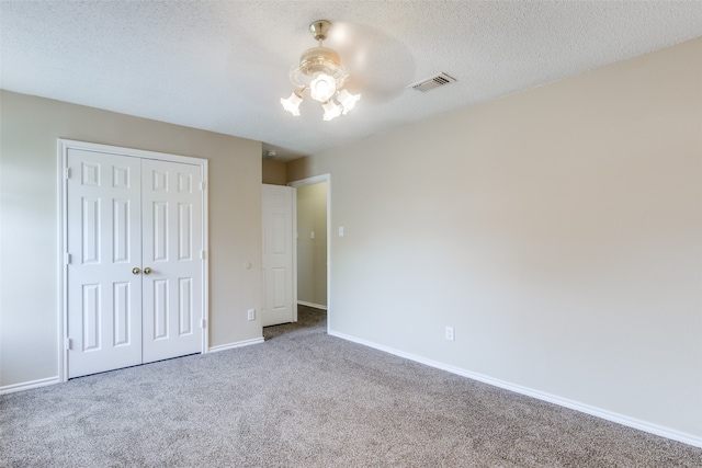 unfurnished bedroom with carpet floors, a textured ceiling, ceiling fan, and a closet