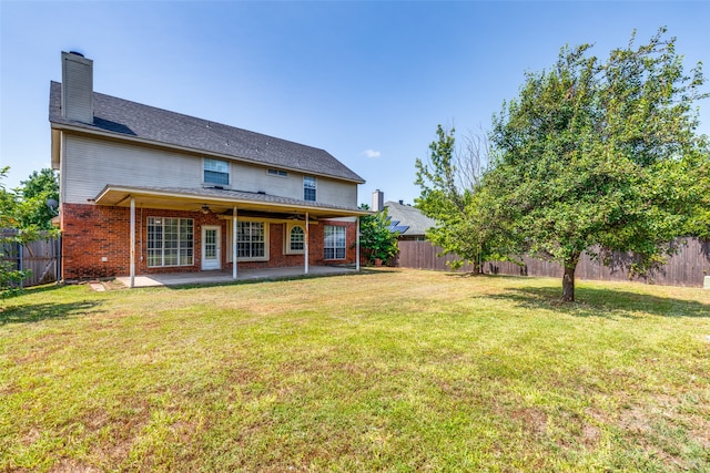 back of property with a lawn, a patio, and ceiling fan