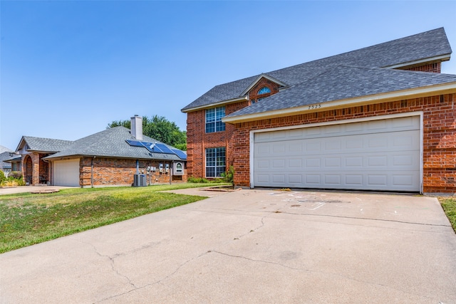 view of front of house featuring central AC unit, a front yard, and a garage