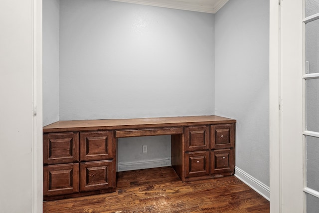 unfurnished office with built in desk, crown molding, and dark hardwood / wood-style flooring