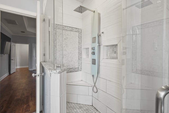 bathroom featuring wood-type flooring, ornamental molding, and a tile shower