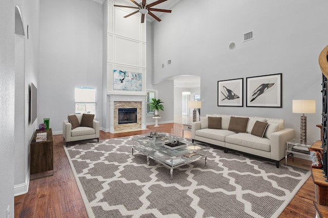 living room featuring a towering ceiling, hardwood / wood-style floors, ceiling fan, and a fireplace