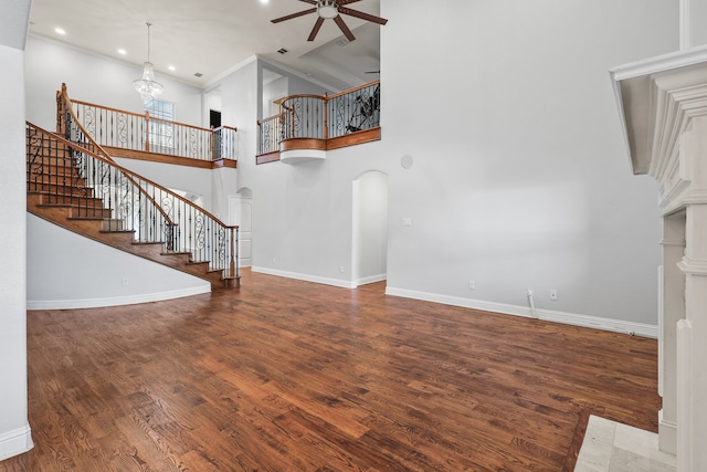 unfurnished living room with hardwood / wood-style flooring, ceiling fan with notable chandelier, and a towering ceiling