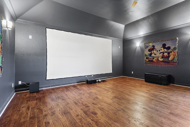 cinema room featuring ornamental molding, vaulted ceiling, and hardwood / wood-style floors