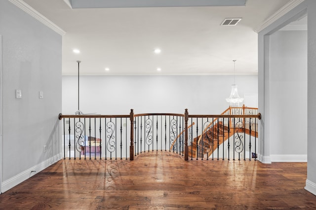 hallway with a notable chandelier, dark hardwood / wood-style floors, and ornamental molding