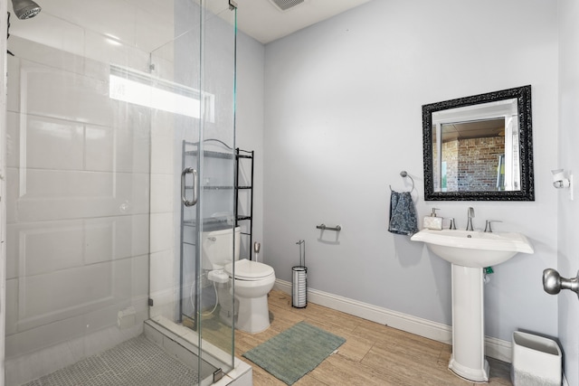 bathroom with hardwood / wood-style floors, toilet, and an enclosed shower