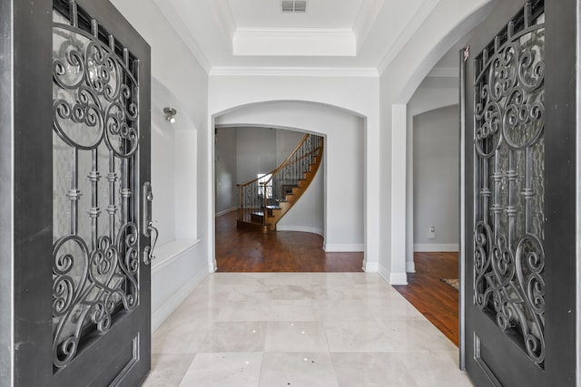 foyer with light wood-type flooring, a tray ceiling, and crown molding