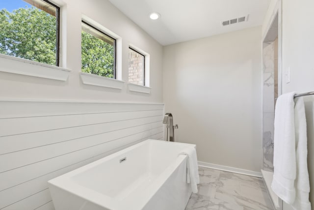 bathroom featuring wooden walls and a bathtub