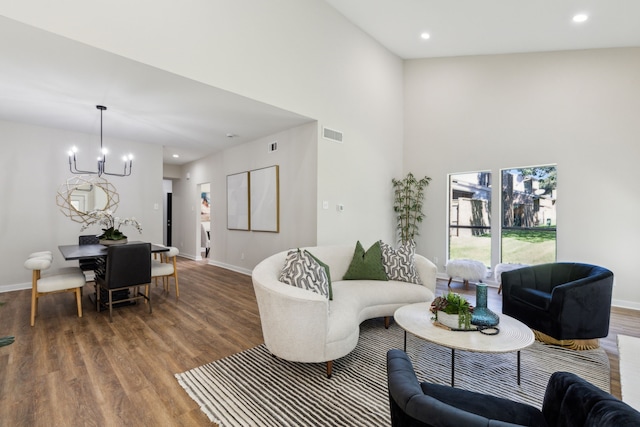 living room featuring high vaulted ceiling, wood-type flooring, and an inviting chandelier