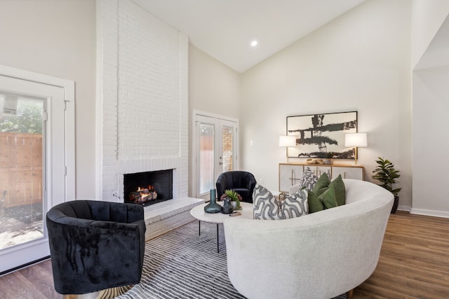 living room with high vaulted ceiling, a brick fireplace, and dark hardwood / wood-style floors