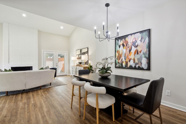 dining room with french doors, wood-type flooring, a chandelier, and a fireplace