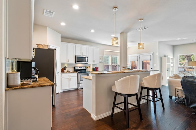 kitchen featuring pendant lighting, appliances with stainless steel finishes, dark wood-type flooring, and white cabinets