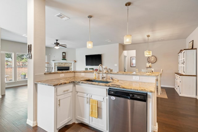 kitchen with white cabinets, a stone fireplace, dishwasher, dark hardwood / wood-style flooring, and sink