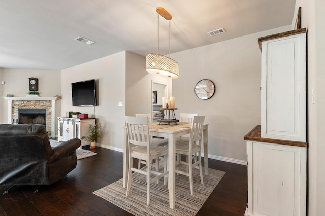 dining room featuring a fireplace and dark wood-type flooring