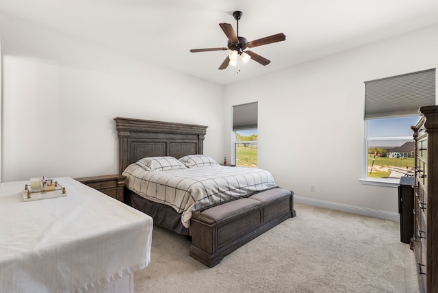 bedroom with ceiling fan, light carpet, and multiple windows