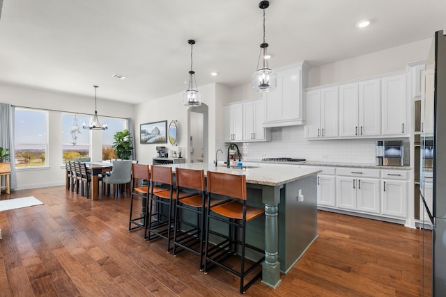 kitchen featuring a kitchen island with sink, dark hardwood / wood-style flooring, and white cabinets