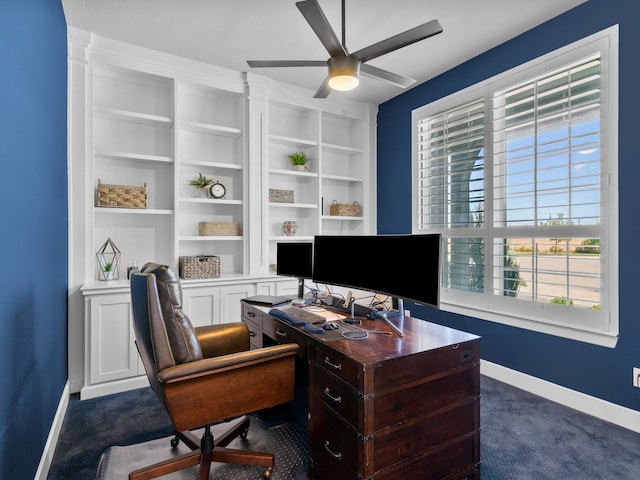 office space featuring ceiling fan, built in shelves, and dark carpet