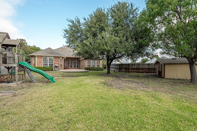 view of yard featuring a playground, a storage shed, and a patio area