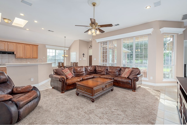 tiled living room with ceiling fan and a skylight